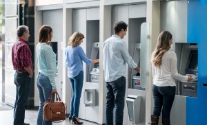 Group of people in a line at an ATM waiting to make a cash withdrawal